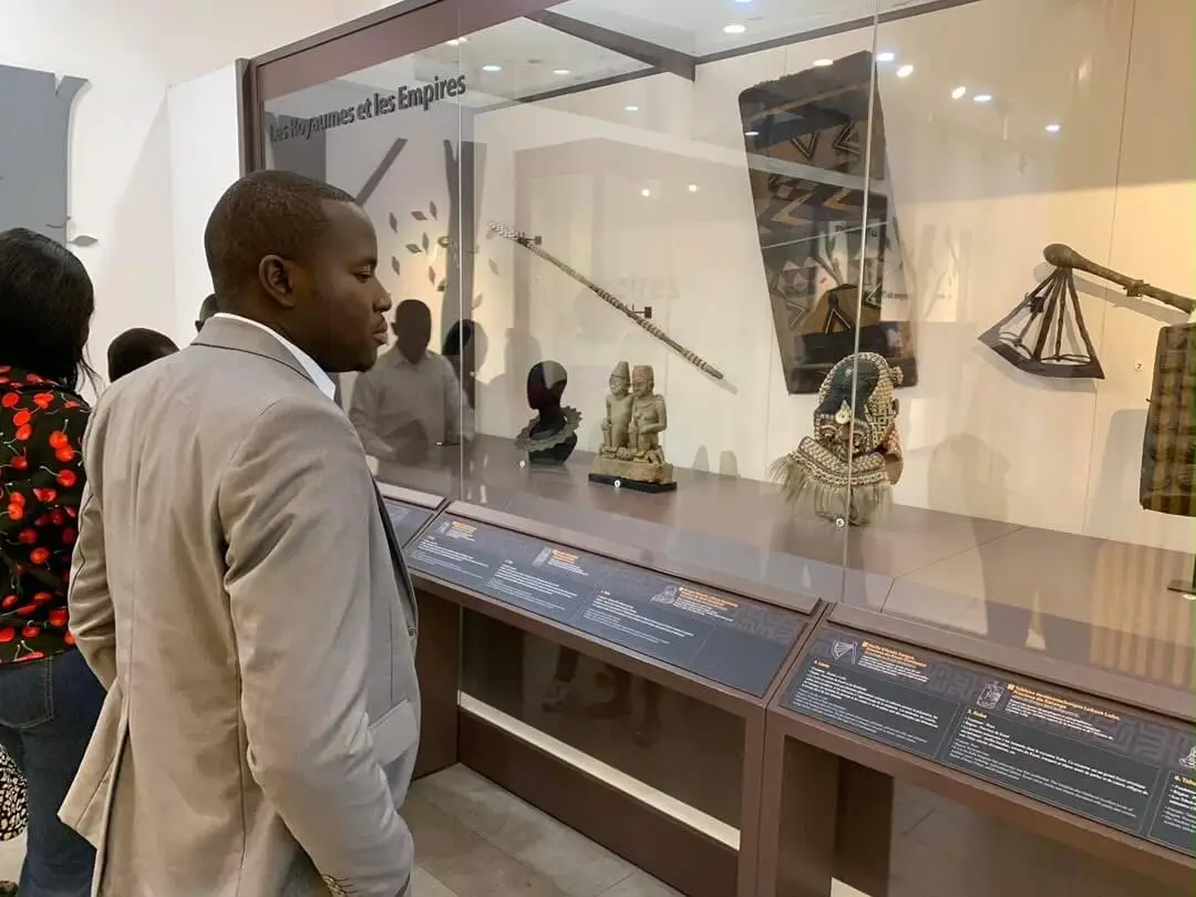 Jacob Dzaringa devant les vitrines de l’exposition « Les Royaumes et les Empires »